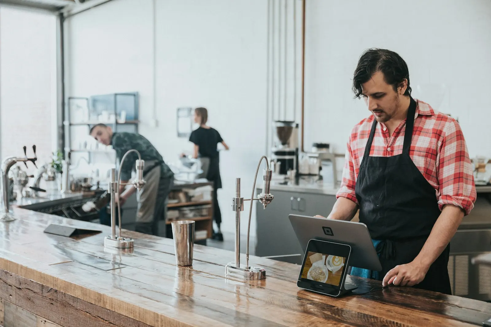 A barista using a tablet at a café counter